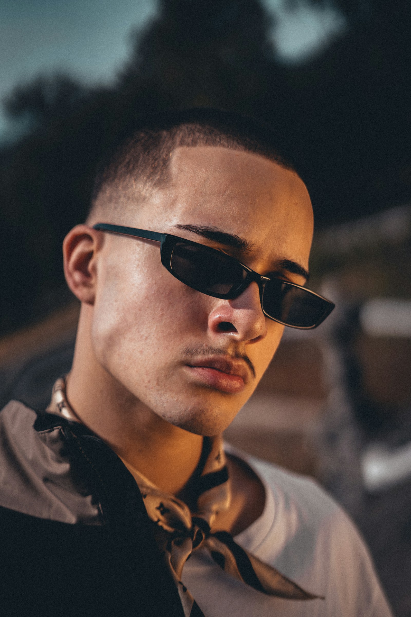 Bald man wearing dark sunglasses and a black collared shirt.