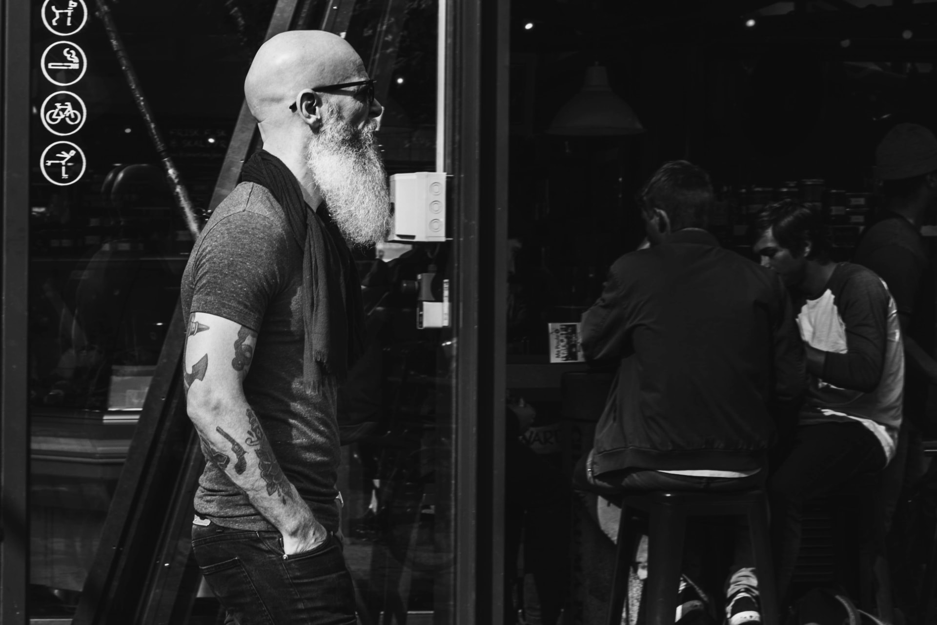 Bald man with a well-groomed beard photographed in a dark editorial style.